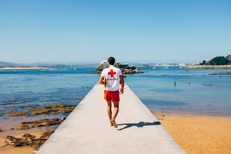 a male lifeguard patrols a concrete pier on a beach scaled