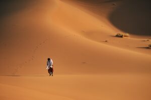 a man walking across a sandy field in the desert