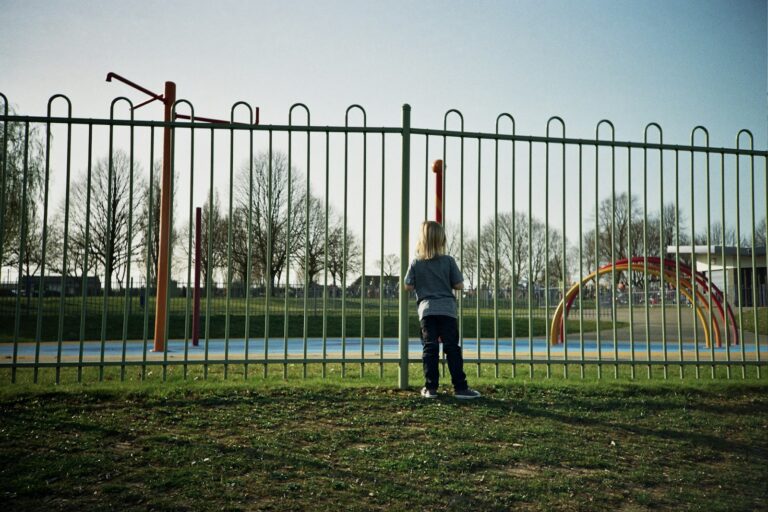 girl in blue jacket and black pants standing on green grass field during daytime