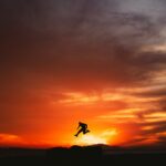 a person jumping into the air at sunset