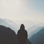 man in hoodie standing in front of the mountain