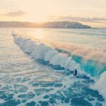 Surfers ride waves at Bondi Beach during a beautiful summer sunset in Australia.