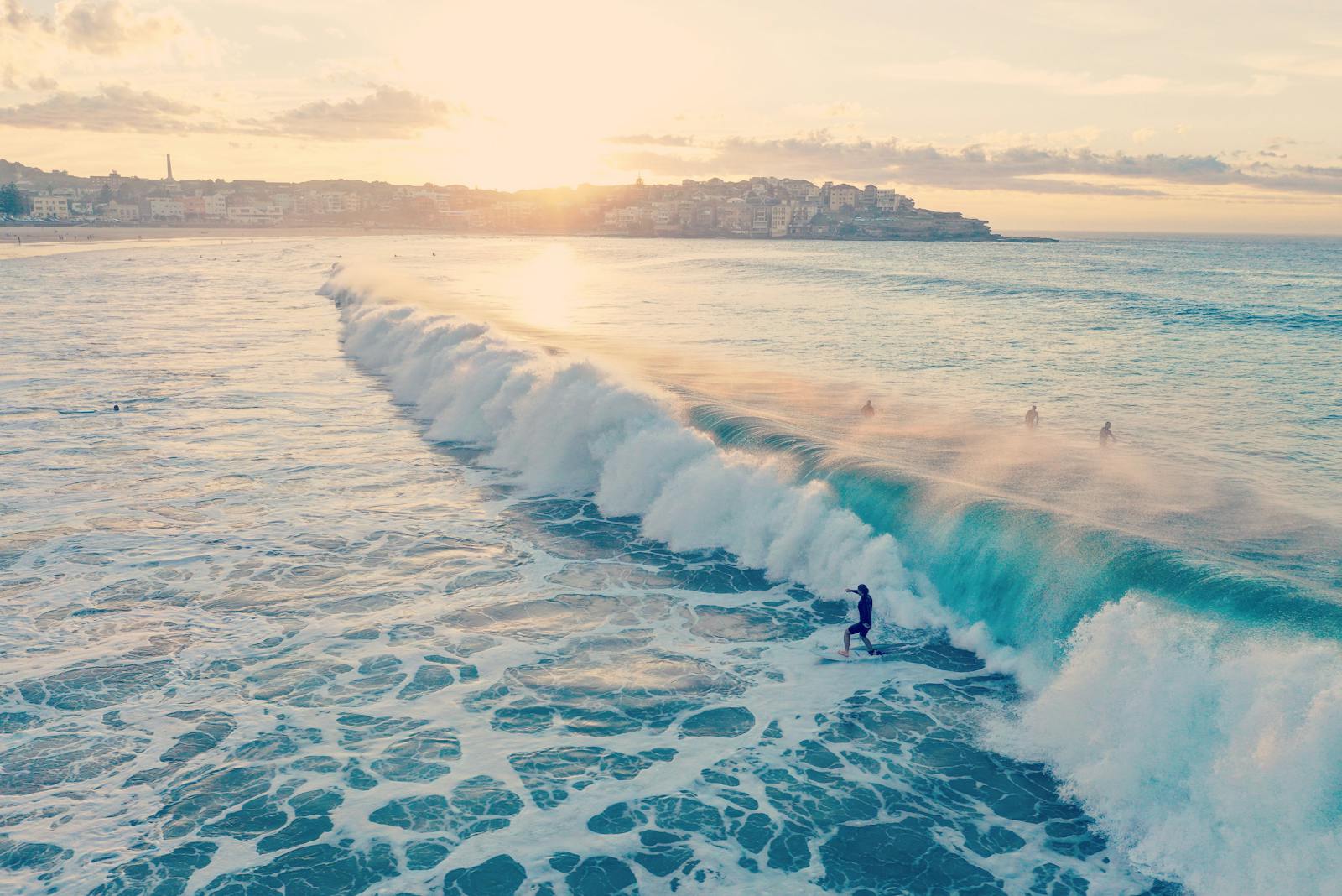 Surfers ride waves at Bondi Beach during a beautiful summer sunset in Australia.