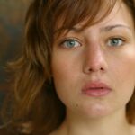 A close-up portrait capturing a young woman's natural beauty with a serious expression.