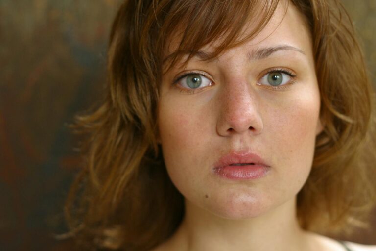 A close-up portrait capturing a young woman's natural beauty with a serious expression.