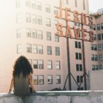 woman in gray top sitting on a building's edge