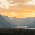 Vibrant sunrise at Glacier National Park, highlighting stunning mountain landscapes and serene river views.