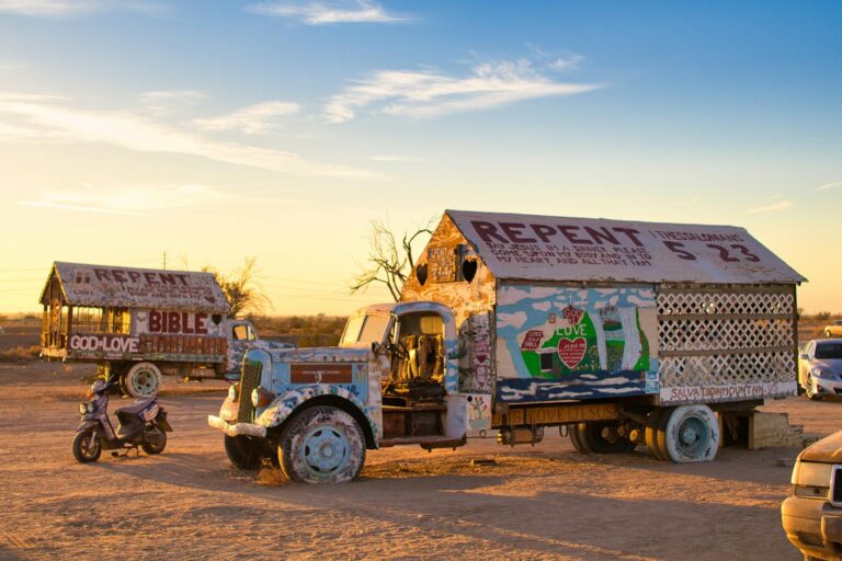 Colorful trucks with religious art at Salvation Mountain captured at sunset, California.