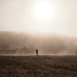 person standing on gray sand during foggy weather