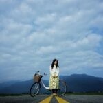 woman standing beside bike on road