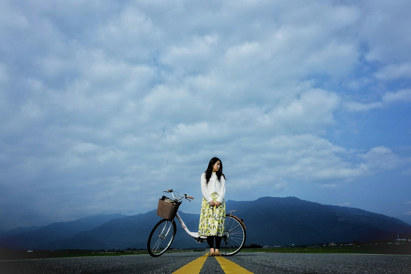 woman standing beside bike on road