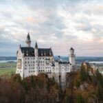 Stunning view of Neuschwanstein Castle in Schwangau, Germany during sunset with scenic landscape.