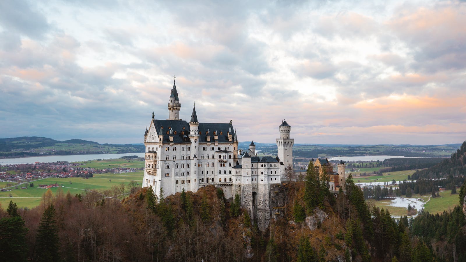 Stunning view of Neuschwanstein Castle in Schwangau, Germany during sunset with scenic landscape.