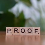 A wooden block spelling proof on top of a table