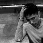 A thoughtful man holds his head.