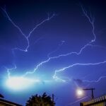Capturing a vivid lightning storm illuminating a nighttime urban scene with dramatic energy.