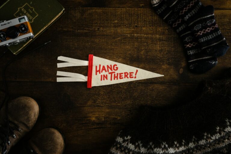 hang in there, a pair of shoes and a pair of socks on a wooden table